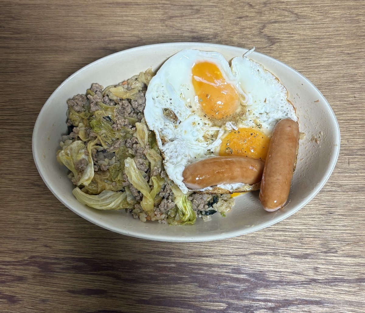 玄米にひき肉とキャベツの炒めをのせ、目玉焼き2個とウインナー2本を添えた晩ごはん